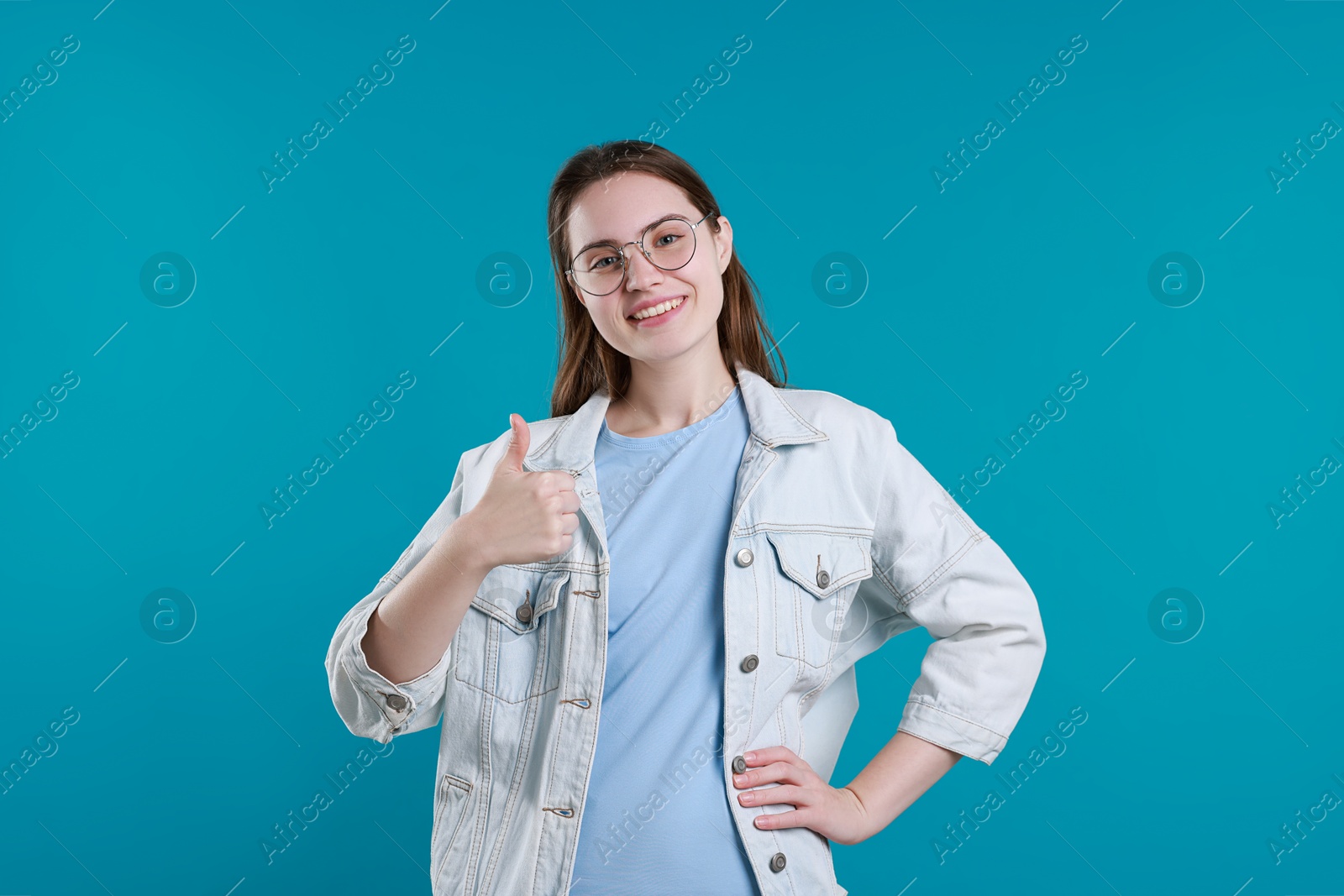 Photo of Happy woman showing thumbs up on light blue background. Like gesture