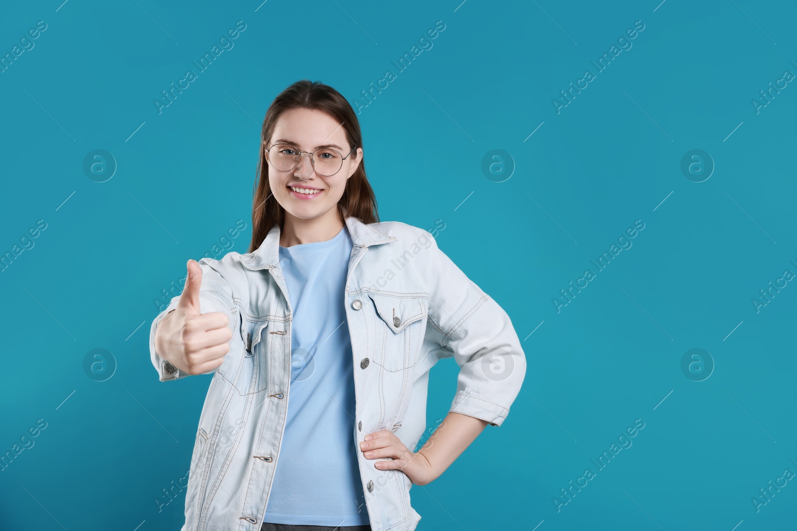 Photo of Happy woman showing thumbs up on light blue background, space for text. Like gesture