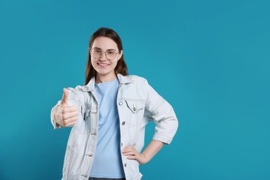 Photo of Happy woman showing thumbs up on light blue background, space for text. Like gesture