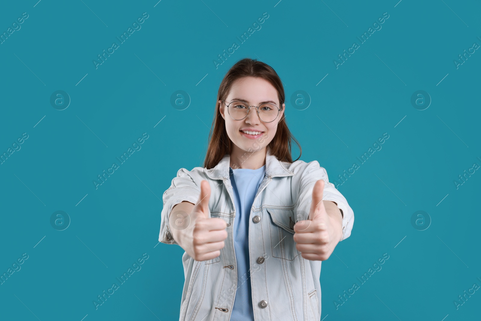 Photo of Happy woman showing thumbs up on light blue background. Like gesture