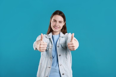 Photo of Happy woman showing thumbs up on light blue background. Like gesture