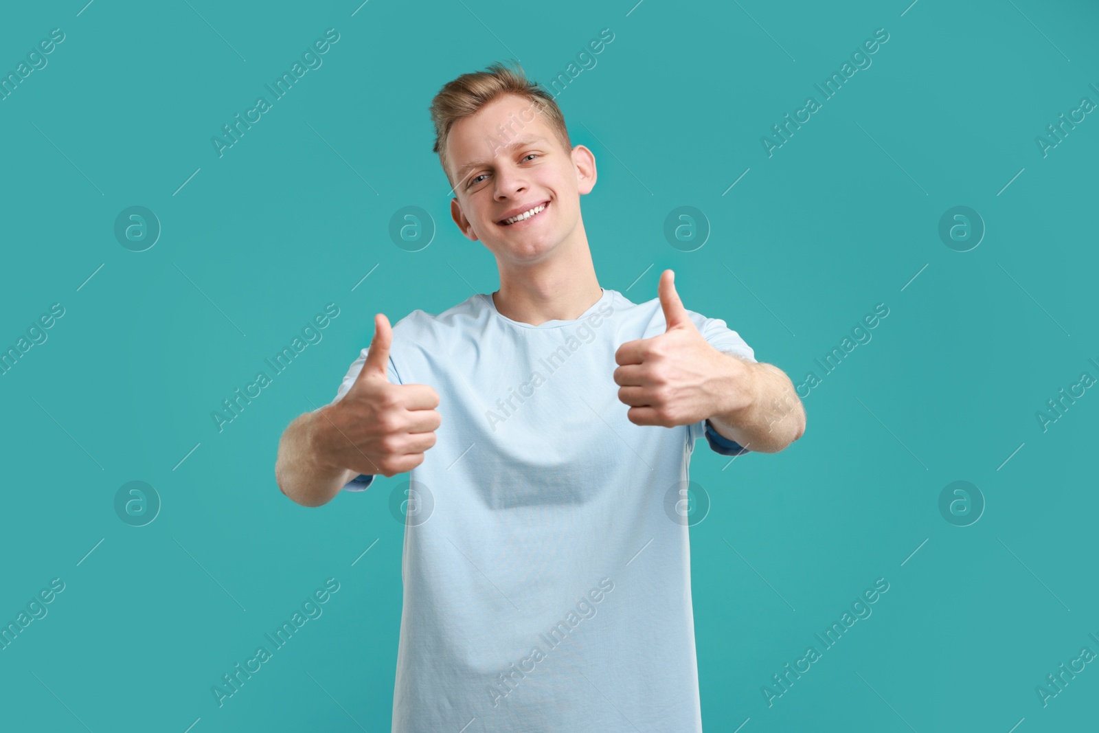 Photo of Happy man showing thumbs up on light blue background. Like gesture