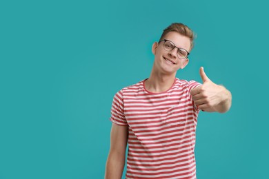 Photo of Happy man showing thumbs up on light blue background, space for text. Like gesture