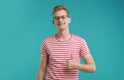 Photo of Happy man showing thumbs up on light blue background. Like gesture