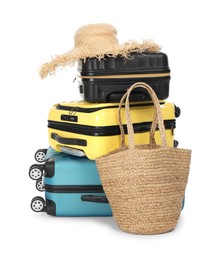 Photo of Many colorful suitcases, beach bag and straw hat isolated on white