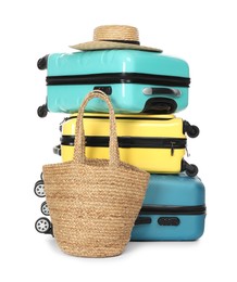 Photo of Many colorful suitcases, beach bag and straw hat isolated on white