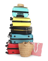 Photo of Stack of colorful suitcases, beach bags and straw hat isolated on white