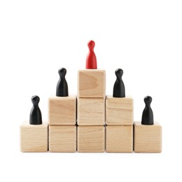 Photo of Human figures on wooden blocks, red one on top against white background. Competition concept