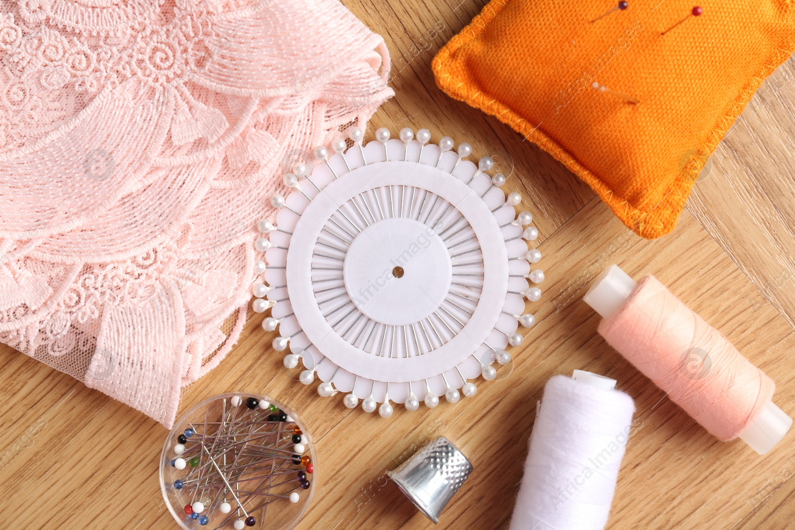 Photo of Sewing threads and other supplies on wooden table, flat lay