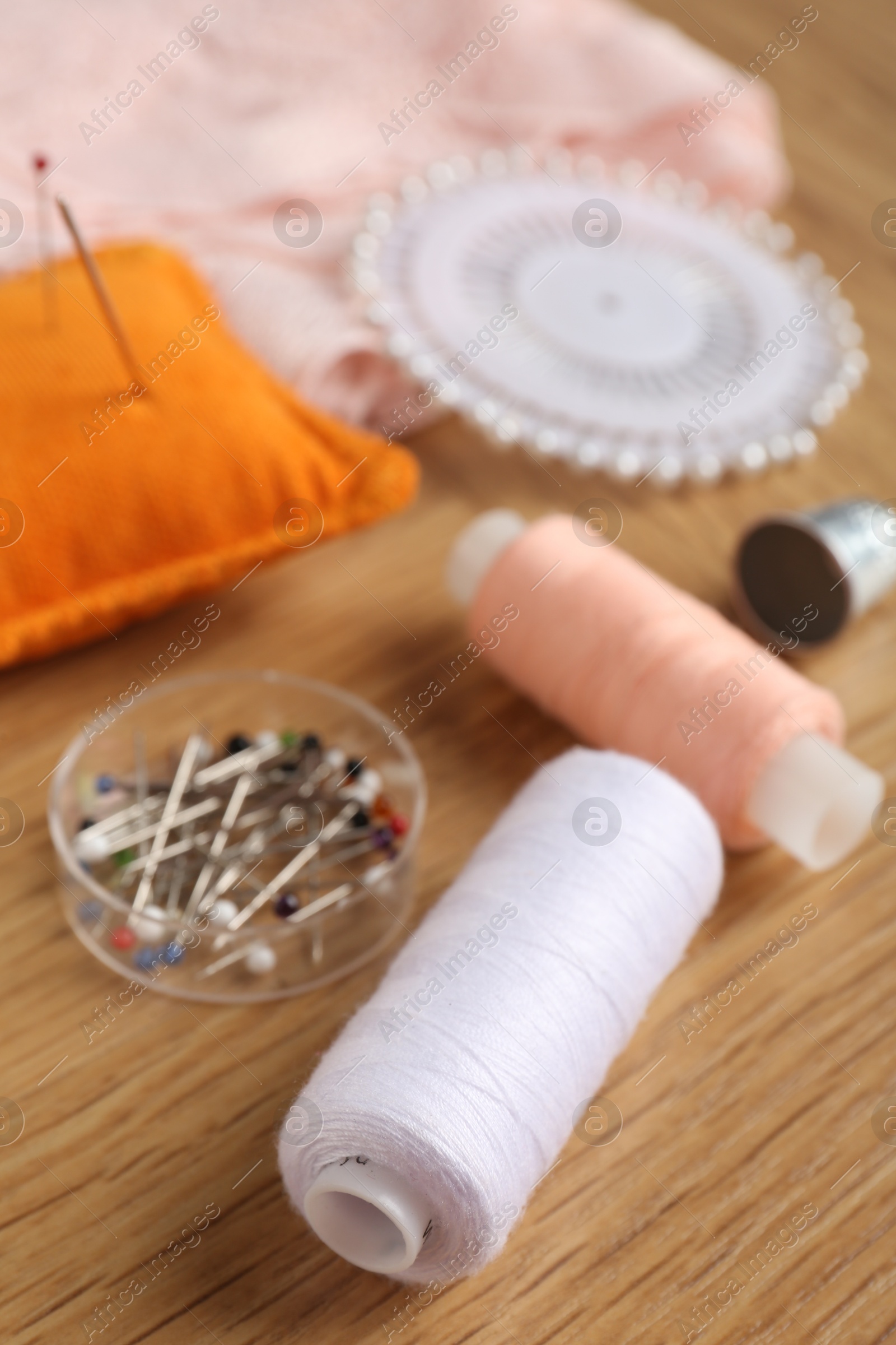 Photo of Sewing threads and pins on wooden table, closeup