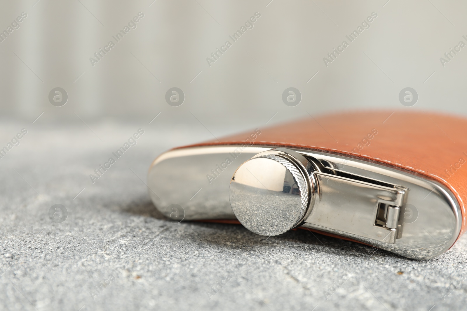 Photo of Hip flask on grey table, closeup view. Space for text