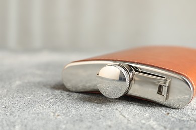 Photo of Hip flask on grey table, closeup view. Space for text