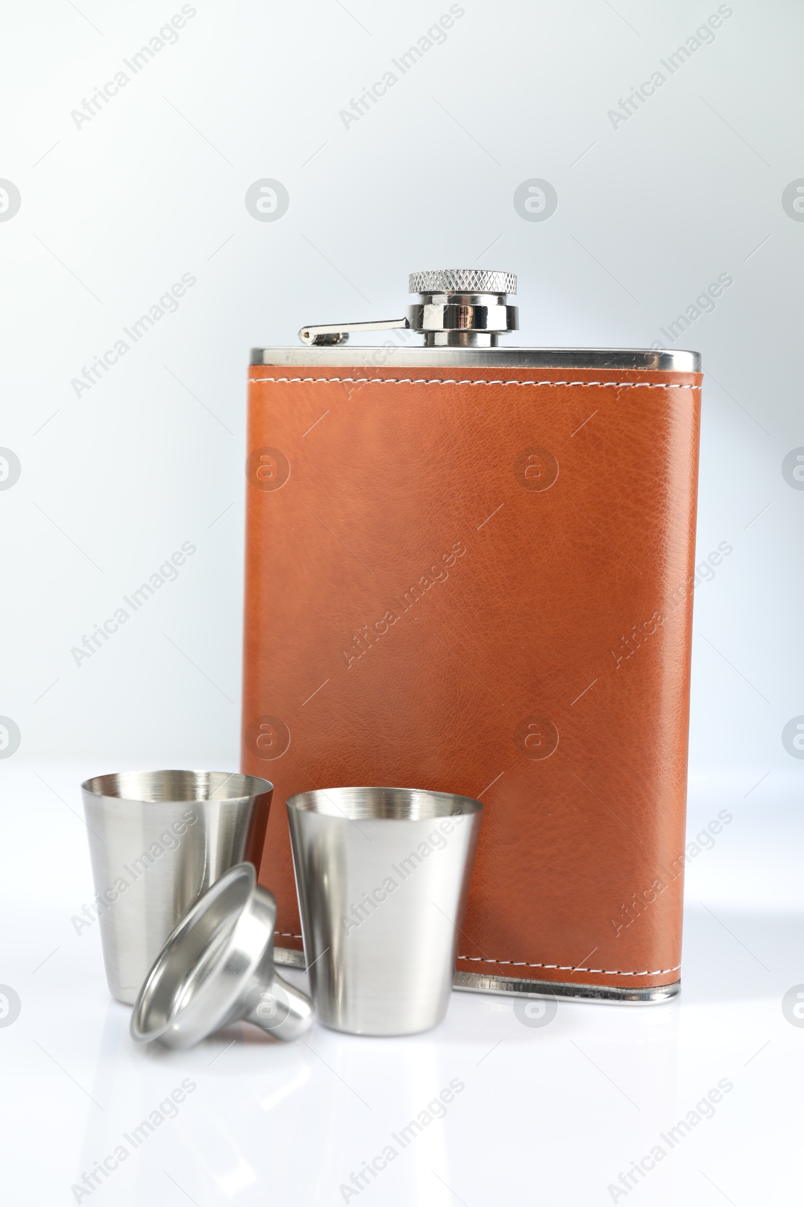 Photo of Hip flask, funnel and cups on white table