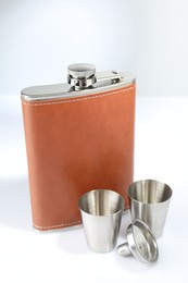 Photo of Hip flask, funnel and cups on white table