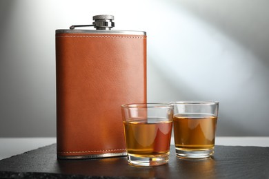 Photo of Hip flask and glasses of whiskey on table