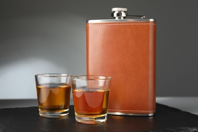 Photo of Hip flask and glasses of whiskey on table