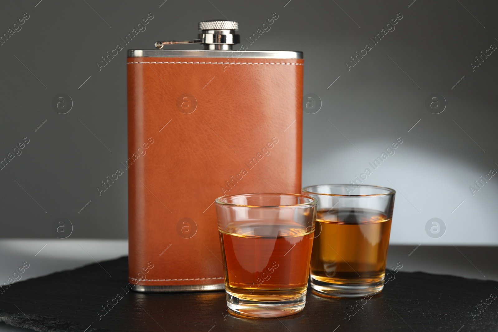 Photo of Hip flask and glasses of whiskey on table