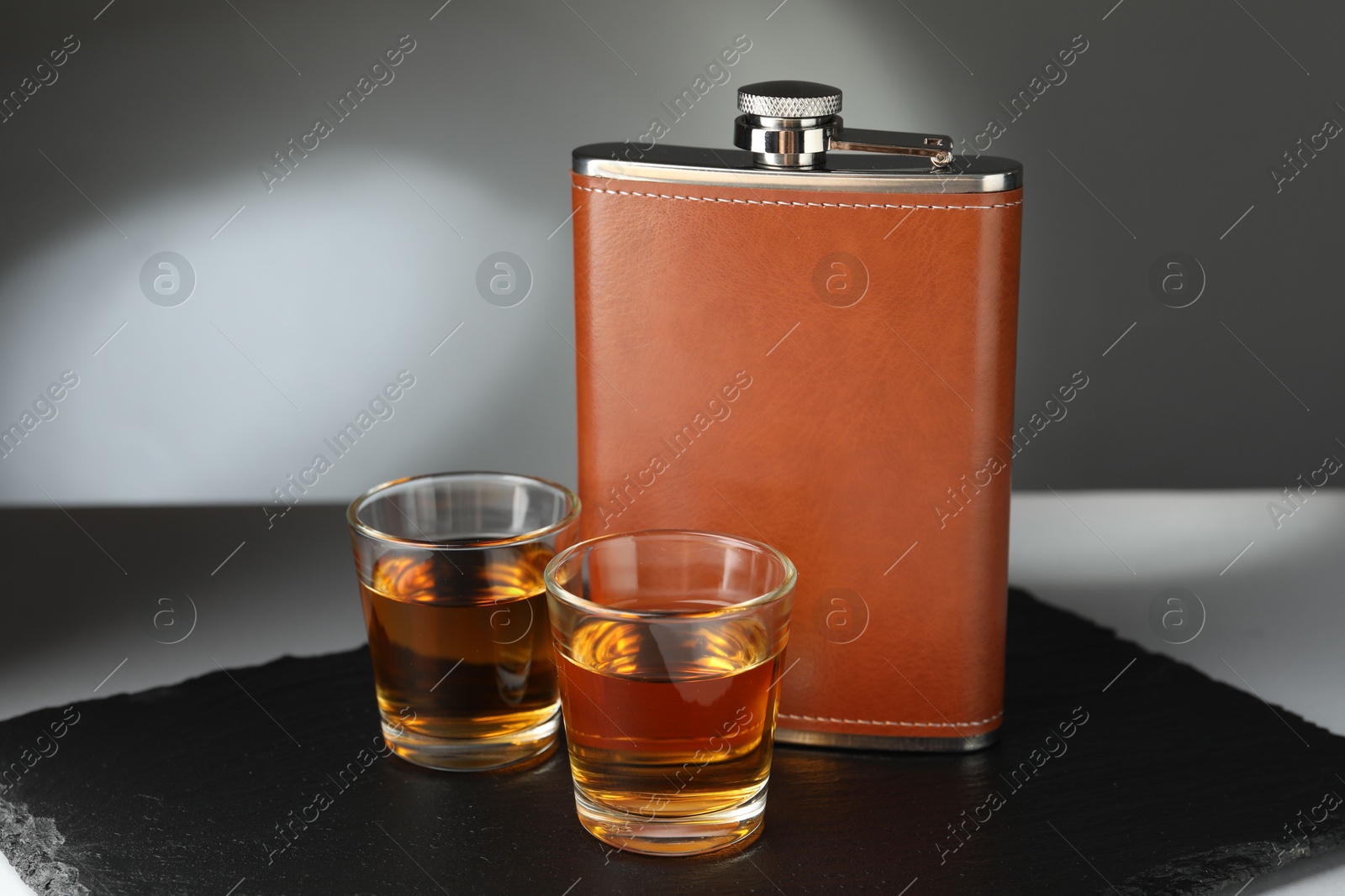 Photo of Hip flask and glasses of whiskey on table