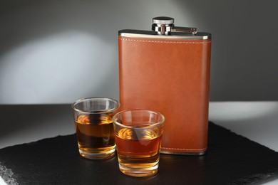 Photo of Hip flask and glasses of whiskey on table