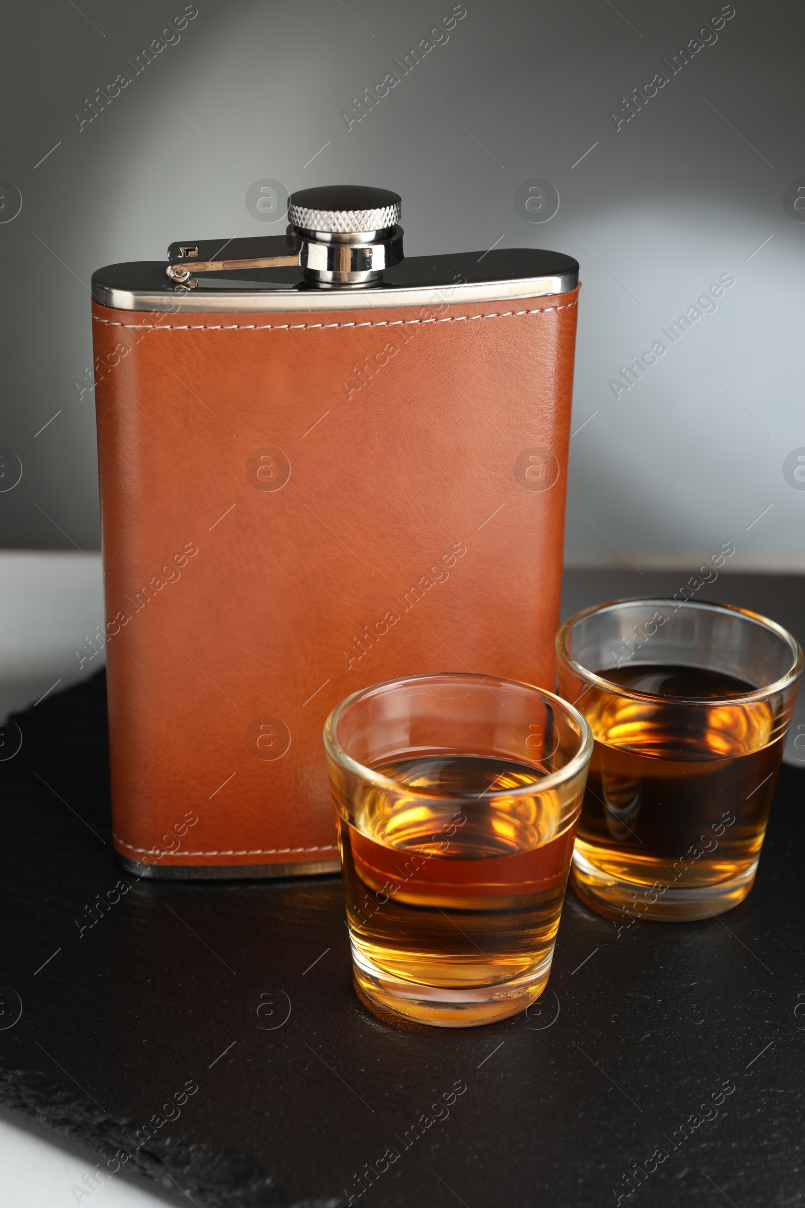 Photo of Hip flask and glasses of whiskey on table