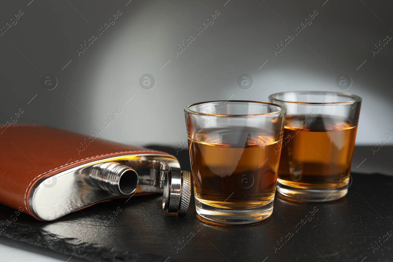 Photo of Hip flask and glasses of whiskey on table