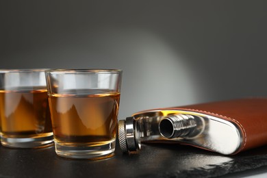 Photo of Hip flask and glasses of whiskey on table