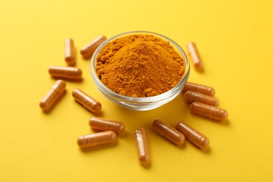 Photo of Turmeric powder in bowl and capsules on yellow background, closeup