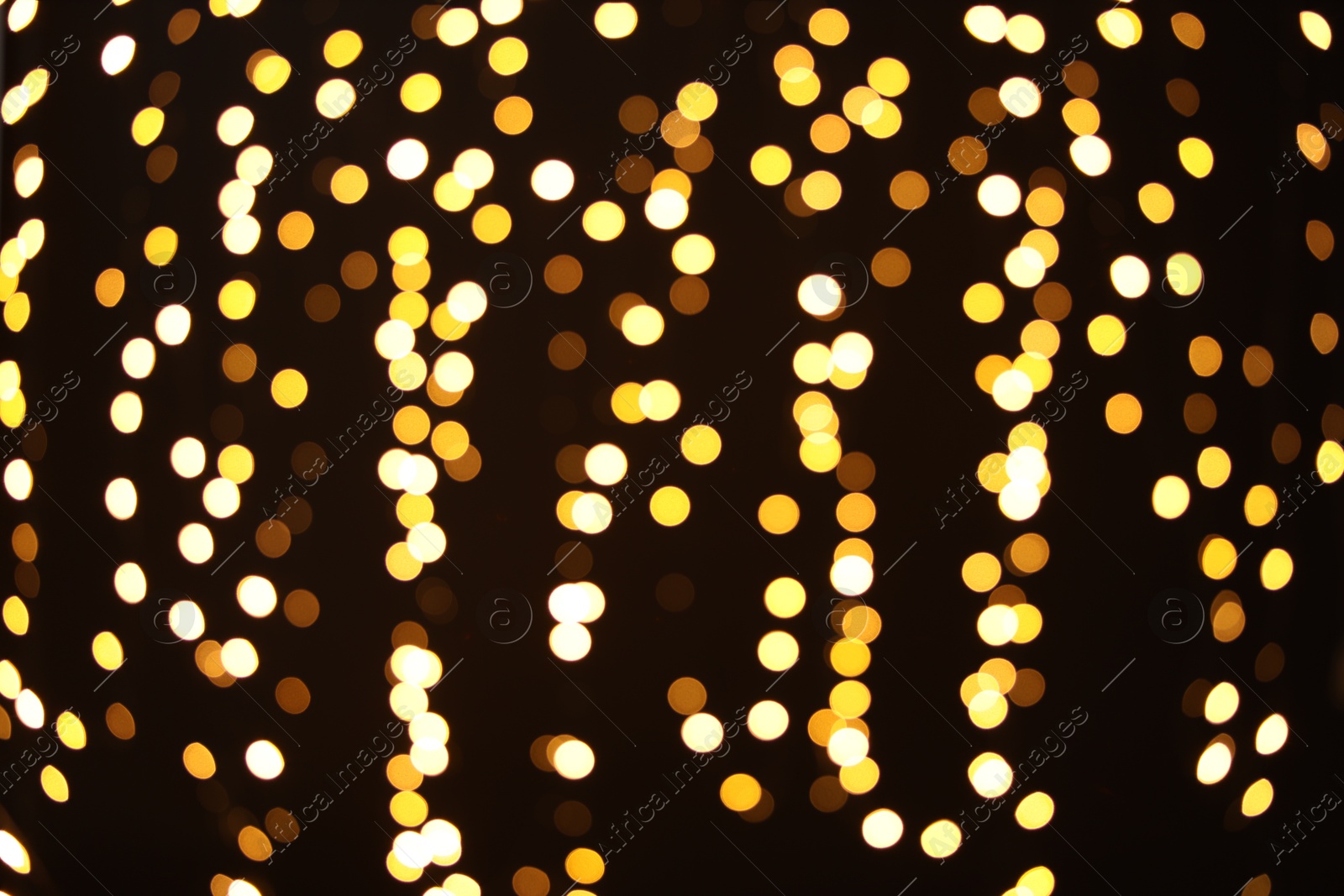 Photo of Blurred view of golden lights on dark background. Bokeh effect