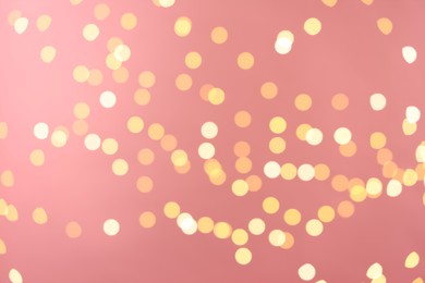 Photo of Blurred view of golden lights on pink background. Bokeh effect