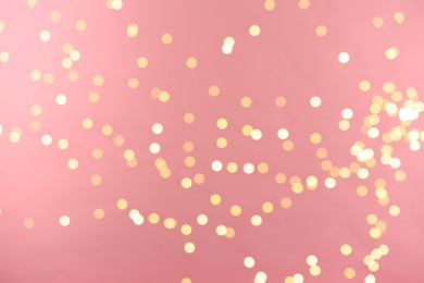 Photo of Blurred view of golden lights on pink background. Bokeh effect