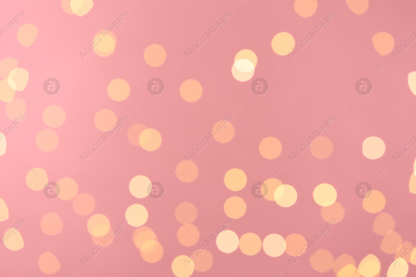 Photo of Blurred view of golden lights on pink background. Bokeh effect