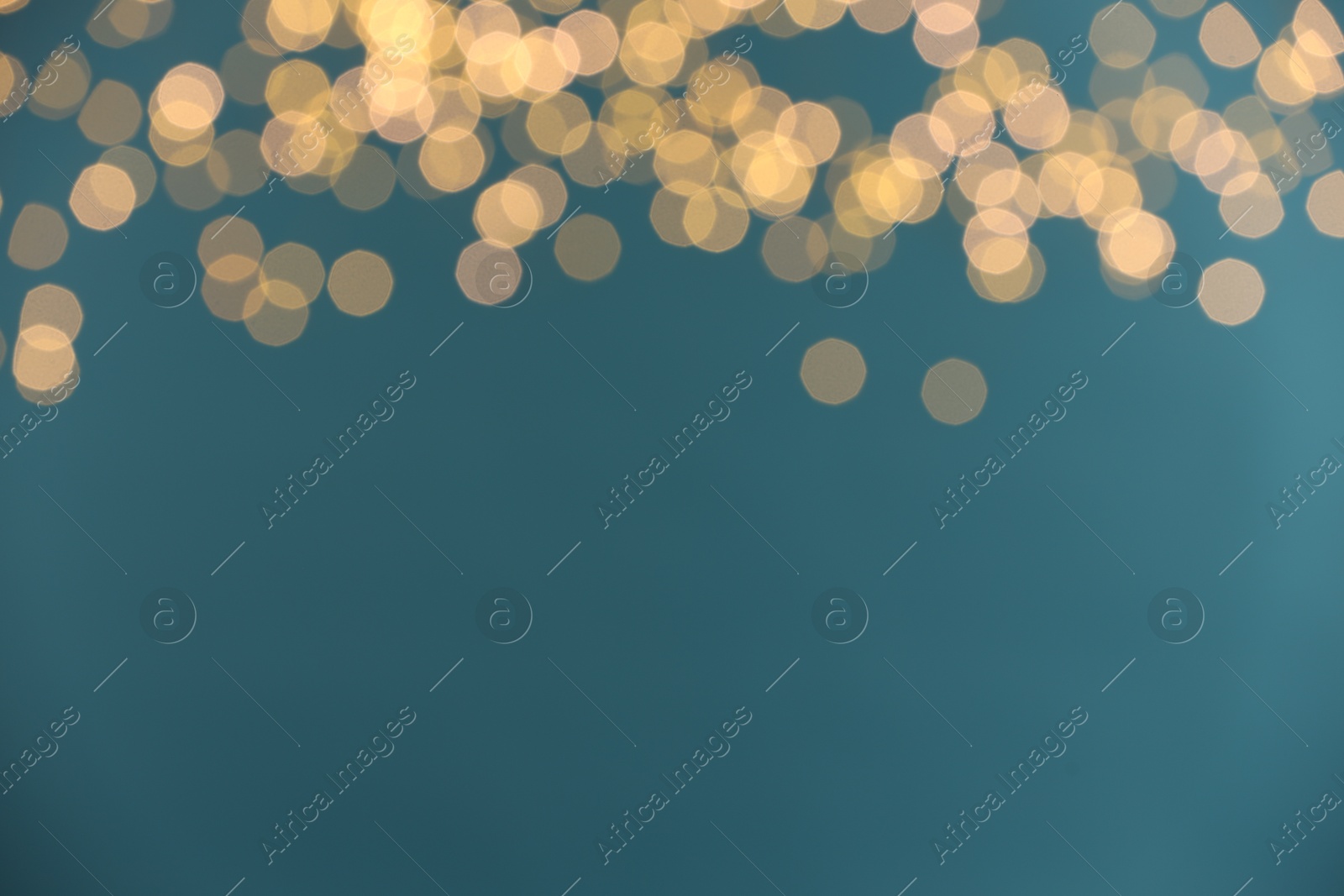 Photo of Blurred view of golden lights on light blue background. Bokeh effect