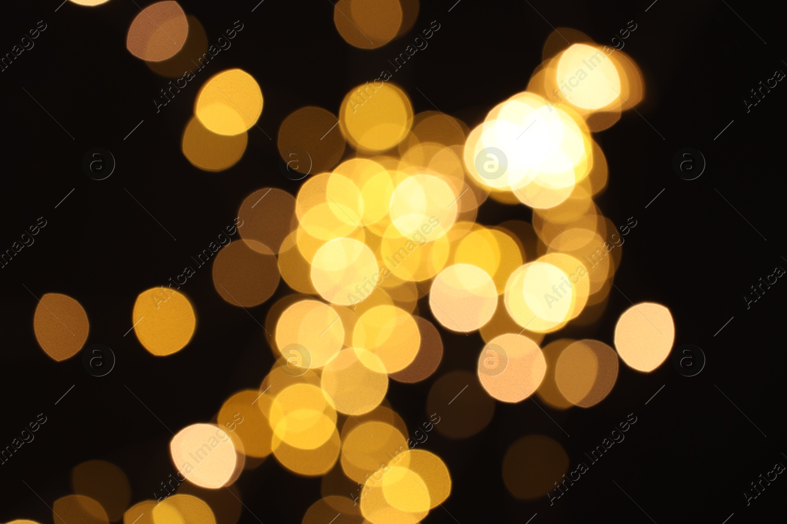 Photo of Blurred view of golden lights on black background, bokeh effect