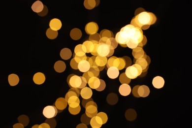 Photo of Blurred view of golden lights on black background, bokeh effect