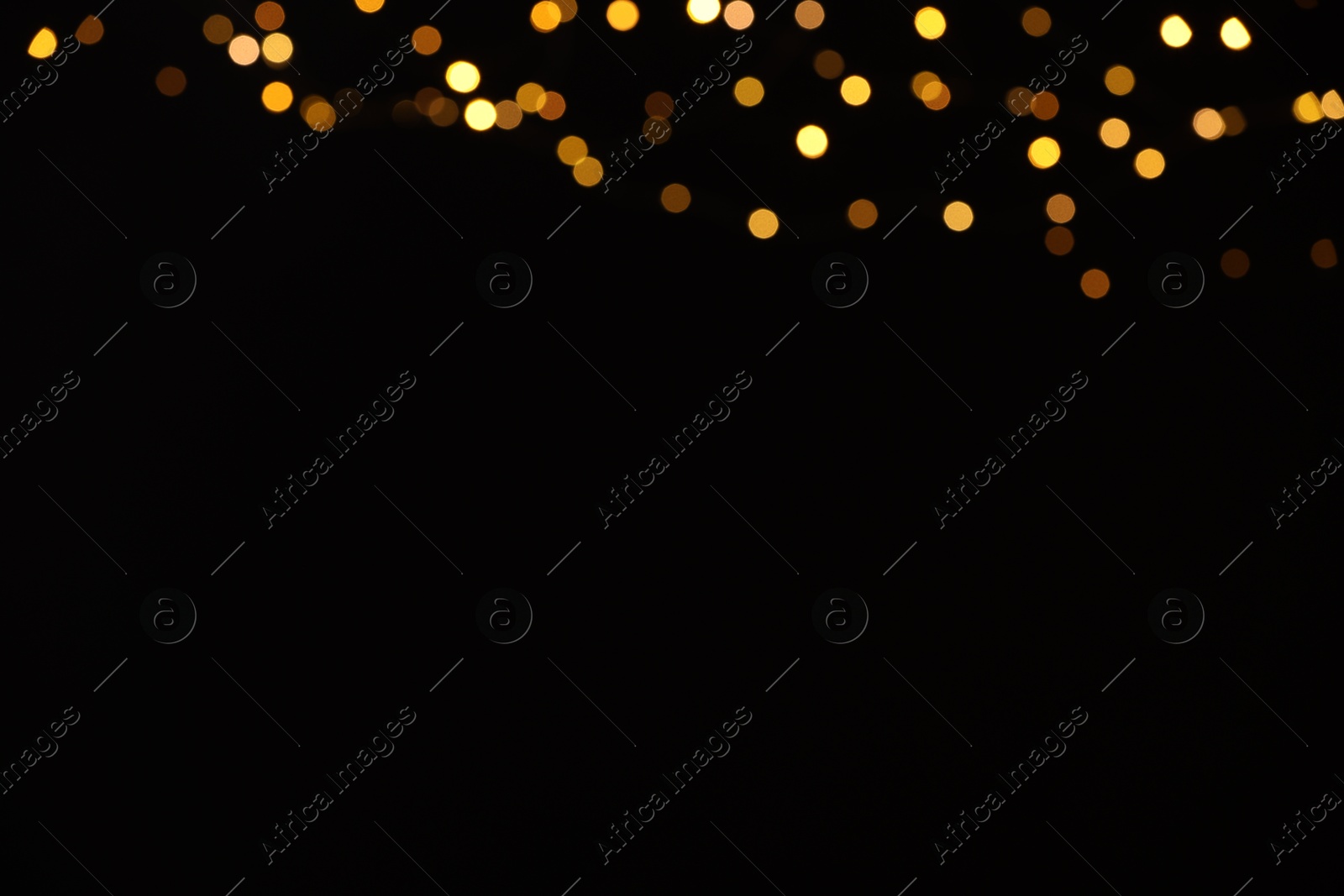 Photo of Blurred view of golden lights on black background, space for text. Bokeh effect