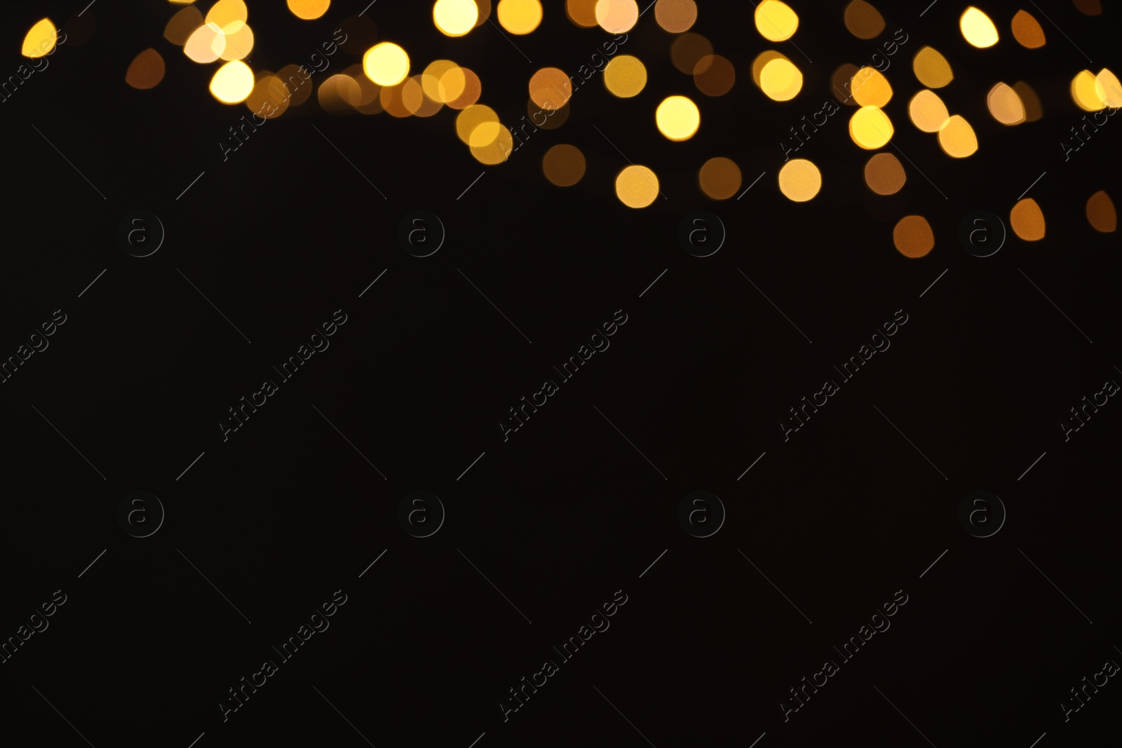 Photo of Blurred view of golden lights on black background, space for text. Bokeh effect