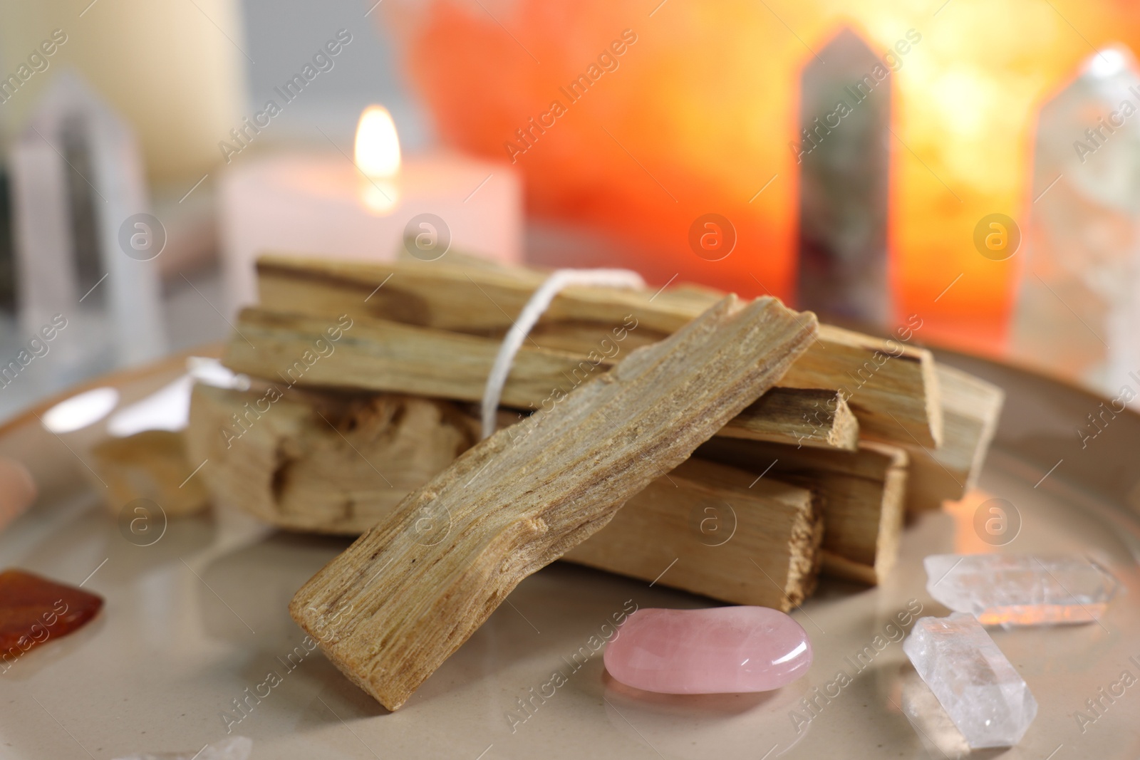 Photo of Palo santo sticks, gemstones and burning candle on table, closeup