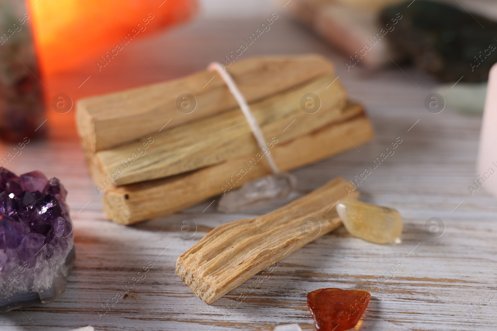 Photo of Palo santo sticks and gemstones on white wooden table, closeup