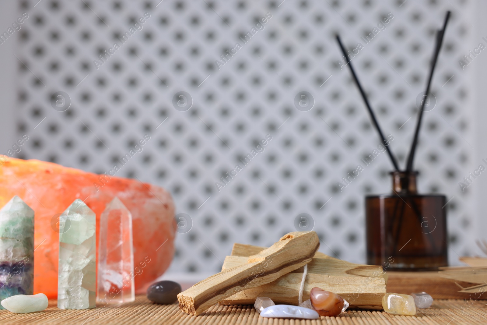 Photo of Palo santo sticks, gemstones and reed diffuser on bamboo mat, closeup