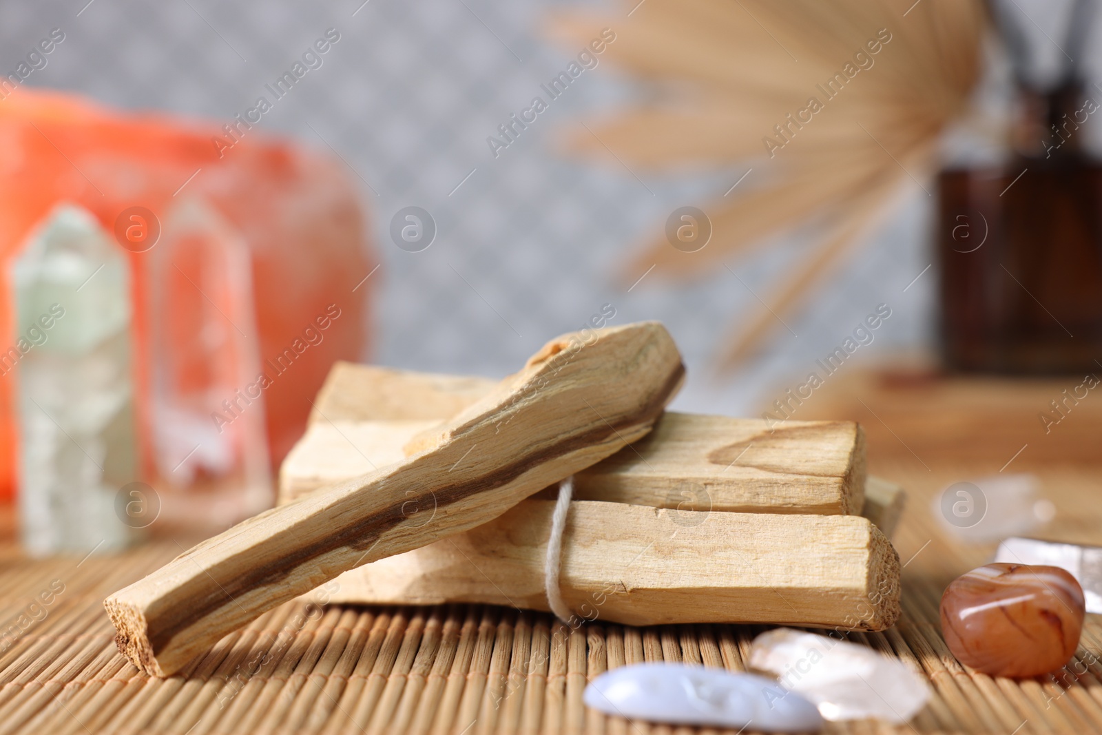 Photo of Palo santo sticks and gemstones on bamboo mat, closeup