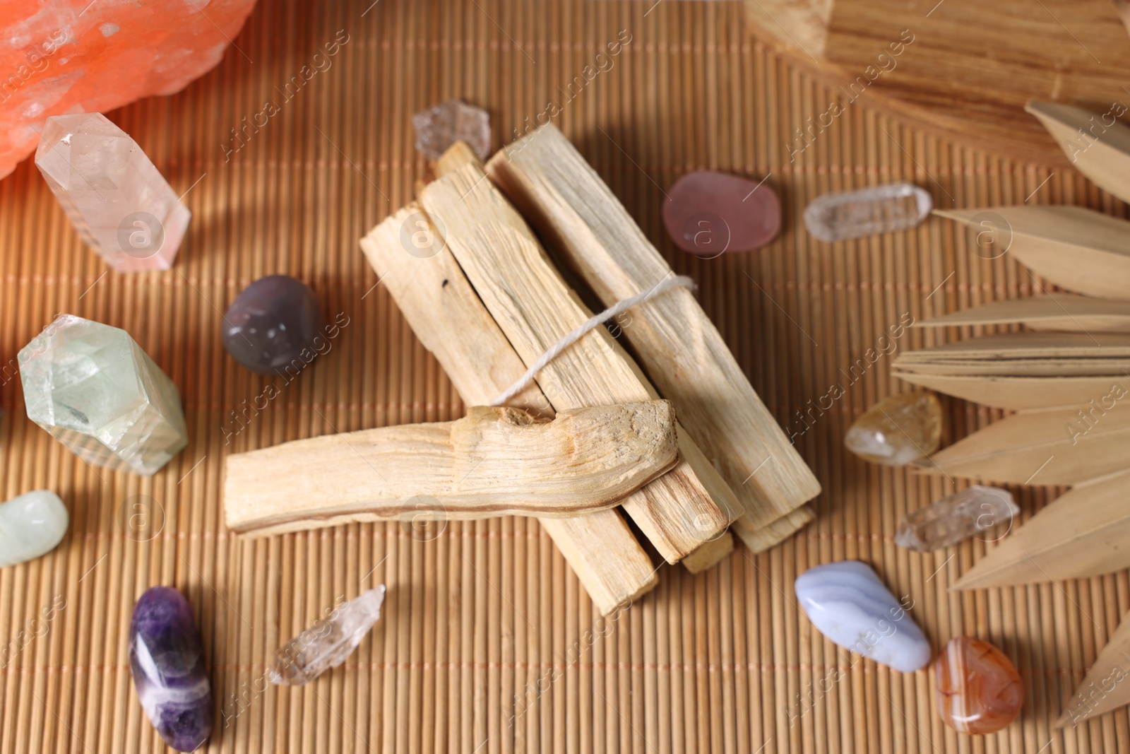 Photo of Palo santo sticks and gemstones on bamboo mat, closeup