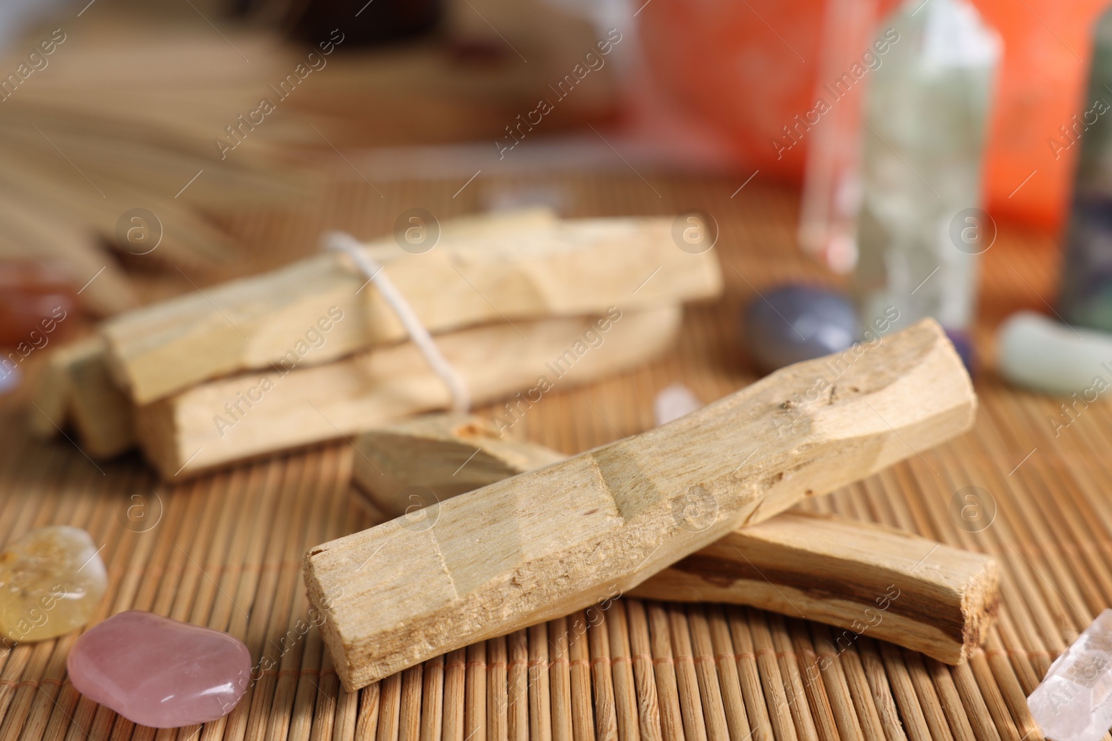 Photo of Palo santo sticks and gemstones on bamboo mat, closeup