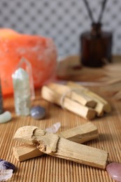 Photo of Palo santo sticks and gemstones on bamboo mat, closeup