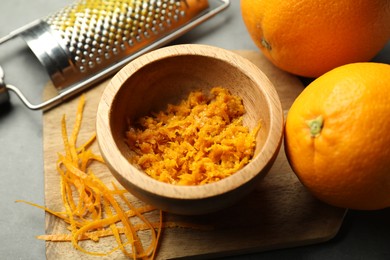 Photo of Orange zest, grater and fresh fruits on gray table, closeup