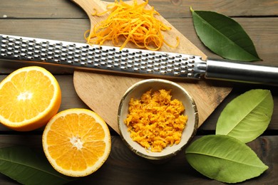 Photo of Orange zest, grater and fresh fruit pieces on wooden table, flat lay