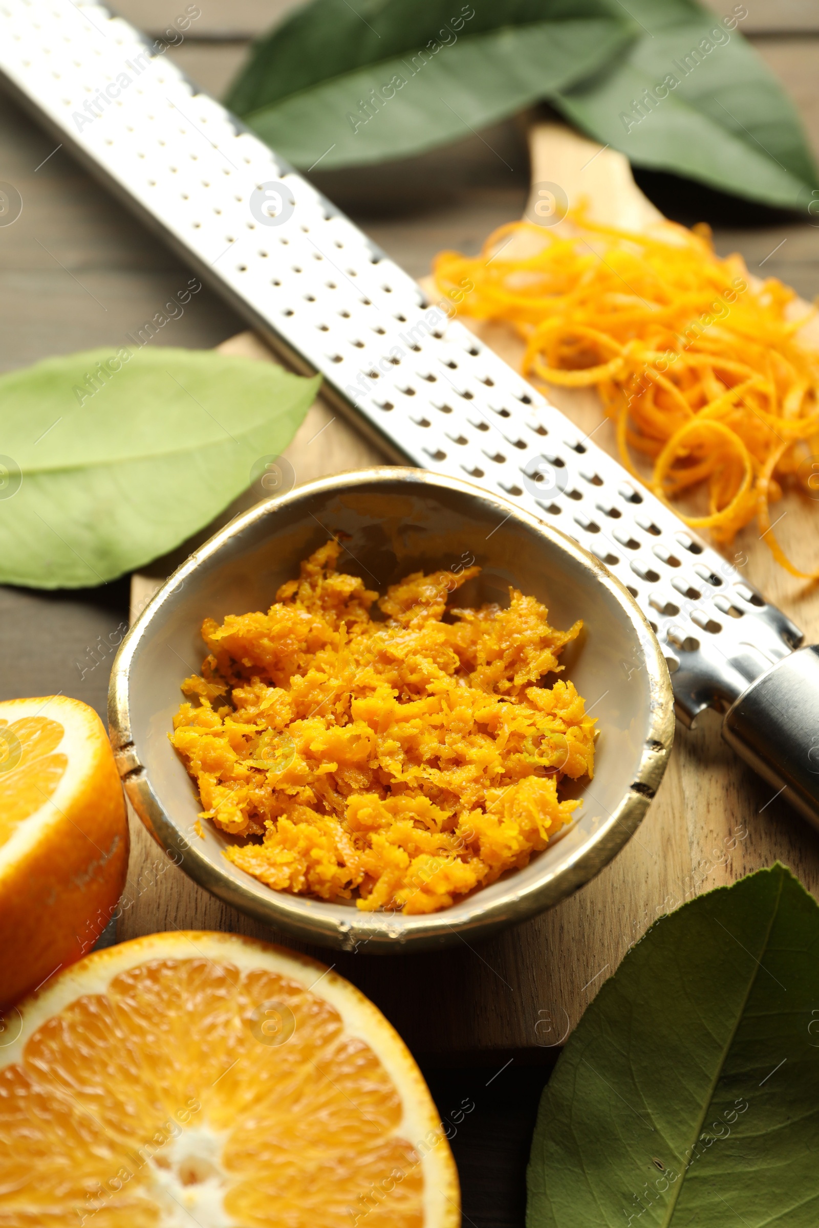 Photo of Orange zest, grater and fresh fruit pieces on wooden table, flat lay