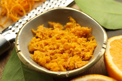 Photo of Orange zest, grater and fresh fruit pieces on table, closeup