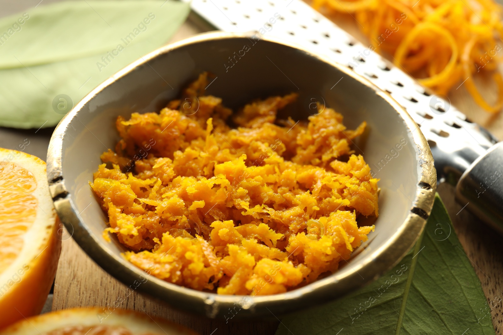 Photo of Orange zest, grater and fresh fruit pieces on table, closeup