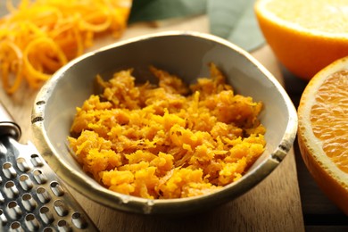 Photo of Orange zest, grater and fresh fruit pieces on table, closeup