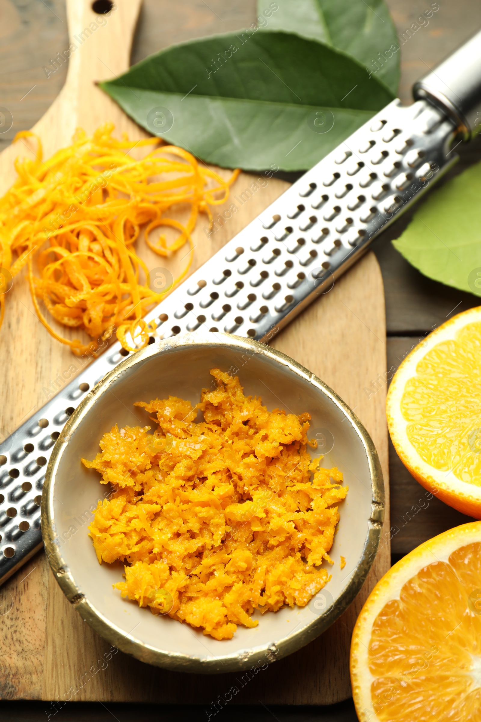 Photo of Orange zest, grater and fresh fruit pieces on wooden table, flat lay